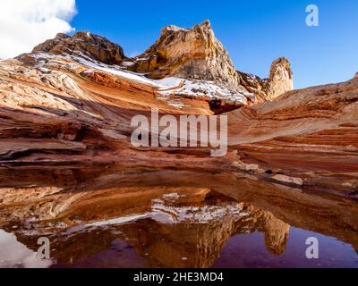 Rare, la neige sur des roches rouges se reflète dans l'eau dans une alcôve de la zone de White Pocket du monument national de Vermilion Cliffs, en Arizona. Banque D'Images