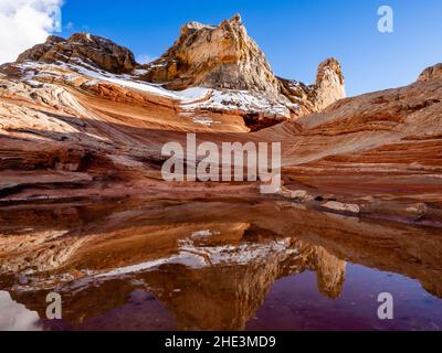 Rare, la neige sur des roches rouges se reflète dans l'eau dans une alcôve de la zone de White Pocket du monument national de Vermilion Cliffs, en Arizona. Banque D'Images