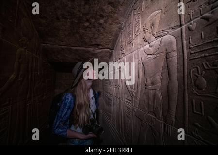 Un touriste admire les murs finement sculptés à l'intérieur du complexe du temple de Philae à Assouan, en Égypte. Banque D'Images