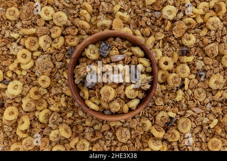 granola croquante avec noix et fruits dans un bol en bois sur fond de muesli, vue du dessus, concept de nourriture saine, délicieux petit déjeuner Banque D'Images