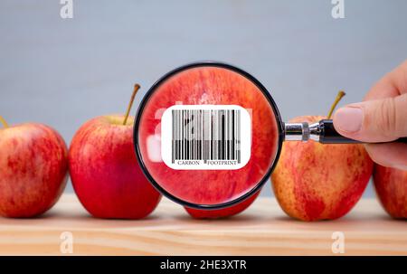 Étiquette de code-barres d'empreinte carbone sur la pomme, agrandie par une loupe, impact environnemental de l'étiquette de durabilité des clients alimentaires sur les aliments Banque D'Images