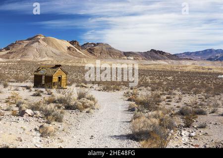 Ruines isolées Old Wooden Vintage chalet en rondins paysage pittoresque désert pics lointains de montagne.Historique Rhyolite Ghost Town Parc national de la Vallée de la mort Banque D'Images