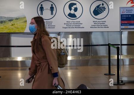 Zaventem, Belgique.8th janvier 2022.Une femme passe devant un panneau rappelant aux gens les mesures contre le COVID-19 à l'aéroport de Bruxelles à Zaventem, en Belgique, le 8 janvier 2022.Selon l'institut de santé belge Sciensano, la Belgique a récemment enregistré une augmentation du nombre de cas de COVID-19, avec une moyenne quotidienne de 15 996 au cours de la période allant du 29 décembre 2021 au 4 janvier 2022.Credit: Zhang Cheng/Xinhua/Alay Live News Banque D'Images