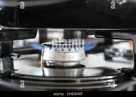 Gros plan de flammes bleues provenant d'une cuisinière à gaz de cuisine à faible chaleur sous une poêle à frire Banque D'Images