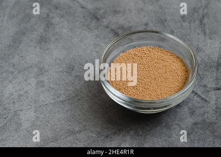 Séchez la levure dans un bol en verre en gros plan sur un fond en marbre gris, dans l'espace de copie Banque D'Images