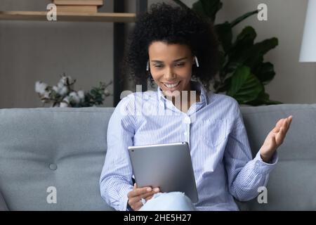 Une jolie femme afro-américaine souriante tient une conversation par appel vidéo. Banque D'Images