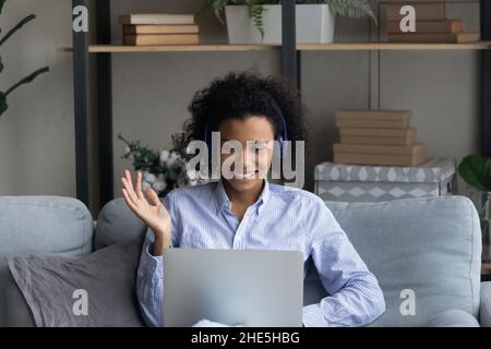 Jeune femme africaine souriante dans un casque tenant un appel vidéo. Banque D'Images