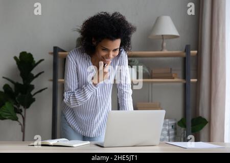 Bonne jeune femme d'affaires africaine pensive qui travaille debout à table. Banque D'Images