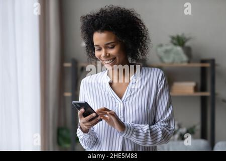 Jeune femme africaine souriante utilisant des applications pour smartphone. Banque D'Images