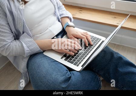 Femme d'âge moyen travaillant à domicile.Fille utilisant un ordinateur portable à la maison, assis près d'une grande fenêtre.Concept de travail à distance Banque D'Images