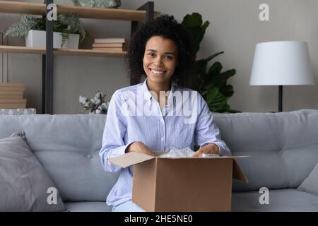 Une jeune femme afro-américaine souriante déballe carton. Banque D'Images