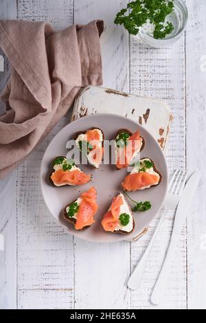 Mini sandwiches avec du saumon, du fromage caillé, du persil et du pain de seigle sous forme de coeurs.Saint-Valentin cuisine créative maison.J'adore le design du petit déjeuner.Séle Banque D'Images