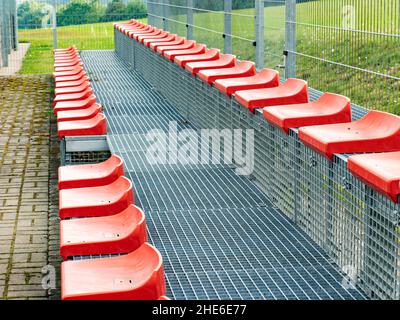 Chaises de Tribune rouges.Sièges de stade en plastique sur deux rangées. Banque D'Images