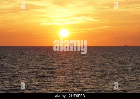 Silhouette de navires marchands à l'horizon de l'océan Pacifique calme pendant le coucher du soleil en automne. Banque D'Images