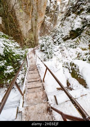 Échelle, escalier en bois et bannister en acier dans un labyrinthe rocheux de grès à la ville d'Adrspach, République tchèque.Visitez le parc en hiver Banque D'Images