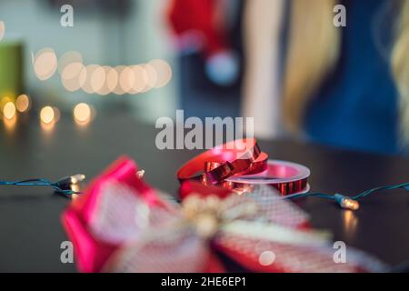 Jeune femme est présente d'emballage. Présent enveloppé dans du papier craft avec un ruban rouge et or pour Noël, anniversaire, fête des mères ou la saint valentin Banque D'Images