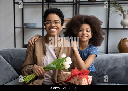 Bonne fille avant adolescent fille embrassant maman tenant boîte cadeau Banque D'Images