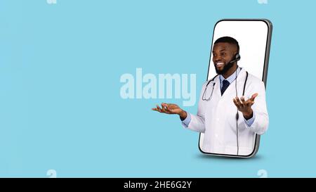 Concept de télémédecine.Black Doctor in Headset Peeking out of Big smartphone Screen Banque D'Images