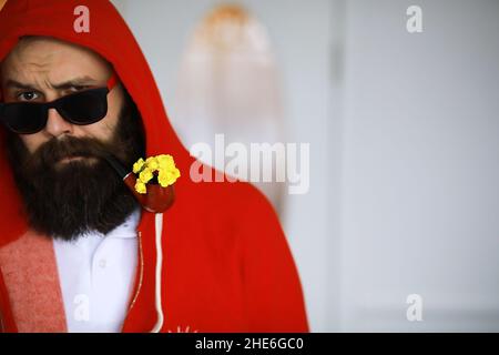 Beau homme ou bûcheron, hipster barbu, barbe et moustache en chemise avec pipe à fumer Banque D'Images