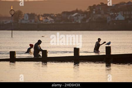 Portobello, Édimbourg, Écosse, Royaume-Uni 9th janvier 2022.Lever de soleil frais et lumineux, température de 4 degrés centigrade pour ceux qui font de l'exercice sur la plage et Firth of Forth.Sur la photo : les personnes en costume mouillé se dirigent vers la rive après un plongeon froid.Credit: Archwhite/Alamy Live News. Banque D'Images