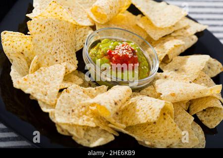 Croustilles nachos avec sauces sur plaque noire Banque D'Images