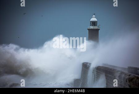 Des vagues géantes battent le phare et la jetée nord qui gardent l'embouchure du Tyne à Tynemouth, en Angleterre Banque D'Images