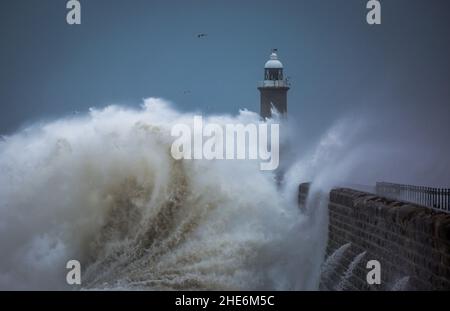 Des vagues géantes battent le phare et la jetée nord qui gardent l'embouchure du Tyne à Tynemouth, en Angleterre Banque D'Images