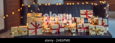 Beaucoup de cadeaux sur une table en bois noir pour vos vacances. Présent enveloppé dans du papier craft avec un ruban rouge et or pour Noël, anniversaire, fête des mères ou Banque D'Images