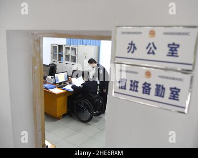 (220109) -- NANNING, 9 janvier 2022 (Xinhua) -- Tan Jianyong (L) travaille à Nanning, dans la région autonome de Guangxi Zhuang, au sud de la Chine, 6 janvier 2022.Tan Jianyong est un policier de 49 ans à Nanning.En 1998, trois ans après qu'il est devenu policier, Tan a été abattu dans la poitrine par un homme armé et s'est paralysé de la poitrine.Encouragé par sa famille, ses collègues et ses amis, Tan a été sorti de la mire de la dépression.Il a progressivement retrouvé la capacité d'autoprise en charge et est revenu à son poste avec des politiques de soutien du travail.Outre son travail, Tan s'est également impliqué dans la communauté, comme il est willi Banque D'Images