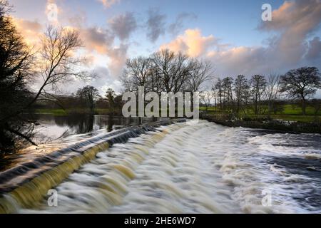 Paysage pittoresque et coloré du ciel et de la campagne (chute d'eau sur les marches du déversoir, force hydraulique) - Rivière Wharfe, Burley dans Wharfedale, Yorkshire, Angleterre, Royaume-Uni. Banque D'Images