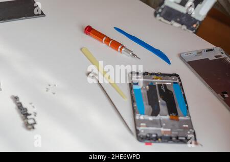 Concept de réparation des smartphones.Outil à main et téléphone démonté reposant sur la table.Fait partie d'une série.Intérieur.Mise au point sélective. Banque D'Images