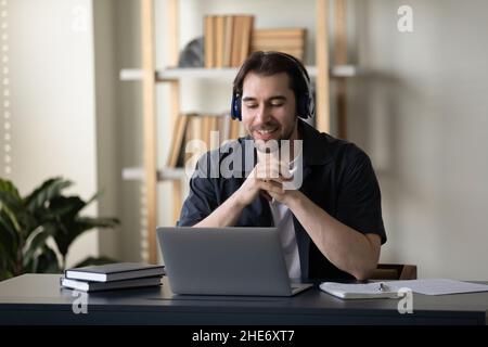 Un jeune homme heureux dans un casque qui communique par appel vidéo. Banque D'Images