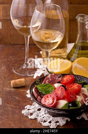 Vin et tomates au basilic dans un décor vintage sur une table en bois Banque D'Images