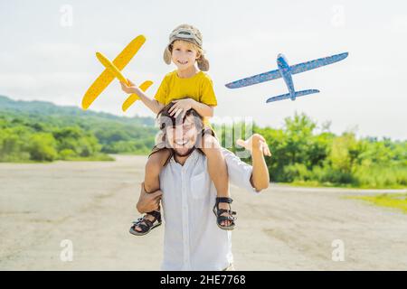 Happy father and son Playing with toy airplane contre l'ancienne piste d'arrière-plan. Concept de voyager avec des enfants Banque D'Images