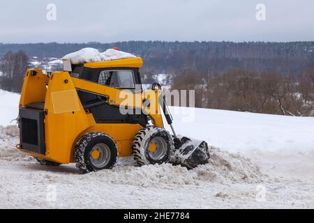 Un petit chariot élévateur orange déneigement de la rue. Banque D'Images