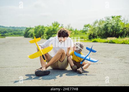Happy father and son Playing with toy airplane contre l'ancienne piste d'arrière-plan. Concept de voyager avec des enfants Banque D'Images