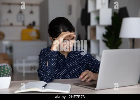 Une femme d'affaires indienne fatiguée et contrariée travaillant à un ordinateur portable Banque D'Images