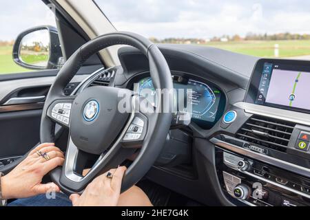 Belle vue de l'intérieur de la BMW iX3 sur la route.Conducteur femelle dans le véhicule.Suède.Uppsala. Banque D'Images