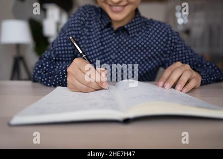 Bonne fille ethnique prenant des notes dans le carnet, liste des tâches Banque D'Images