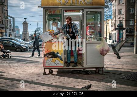 Belgrade, Serbie, 5 janvier 2022 : une vendeuse nourrissant des pigeons de maïs soufflé Banque D'Images