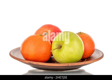 Deux pommes juteuses, vertes, rouges et deux tangerines sur une plaque d'argile rapprochée, isolées sur blanc. Banque D'Images