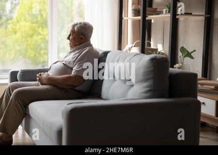Un homme de 80s ans détendu et heureux assis sur un canapé à la maison. Banque D'Images