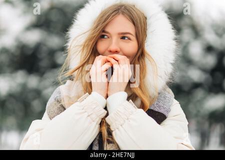 Bonne fille se réchauffant les mains dans des vêtements chauds d'hiver.Un portrait attrayant en plein air par temps froid.Congélation d'une femme à l'extérieur Banque D'Images