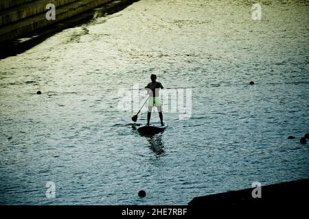 Silhouette d'un homme surfant sur un paddle board, surf actif sur un SUP (stand up paddle board). Banque D'Images