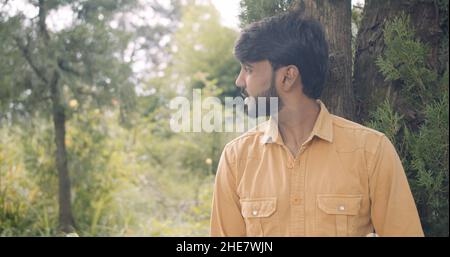 Jeune homme indien beau contre les arbres dans un parc Banque D'Images