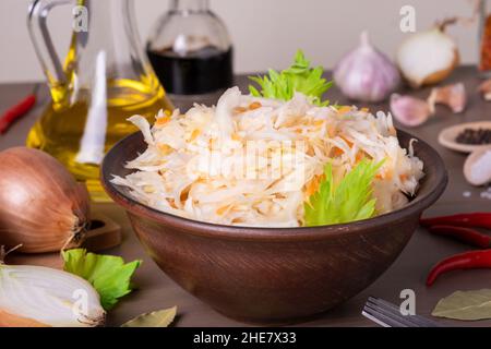 Gros plan du chou fermenté de choucroute dans un bol en céramique de choucroute sur table avec épices et ingrédients.Une alimentation saine et saine.Cuisine russe.Sélection Banque D'Images