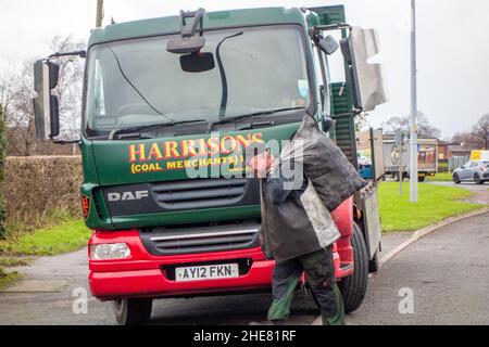 Coalman avec sac de charbon sur son dos livrant du charbon à une maison privée à partir d'un wagon de charbon Banque D'Images