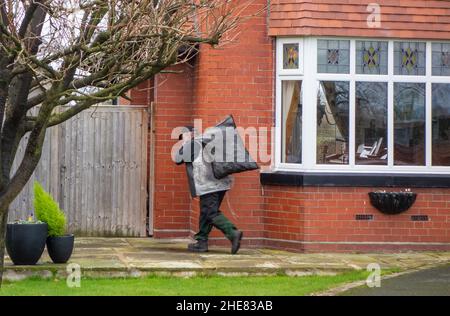 Coalman charbon homme avec sac de charbon sur son dos livrant du charbon à une maison privée Banque D'Images