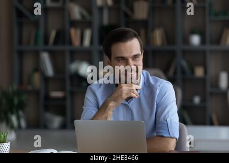 Homme d'affaires souriant et souriant, à distance, assis au bureau Banque D'Images