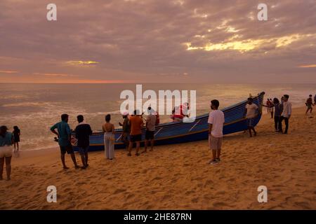 VARKALA, KERALA, INDE - 31 DÉCEMBRE 2021: Des hommes poussant le bateau à la mer pour prendre des touristes pour un voyage. Banque D'Images